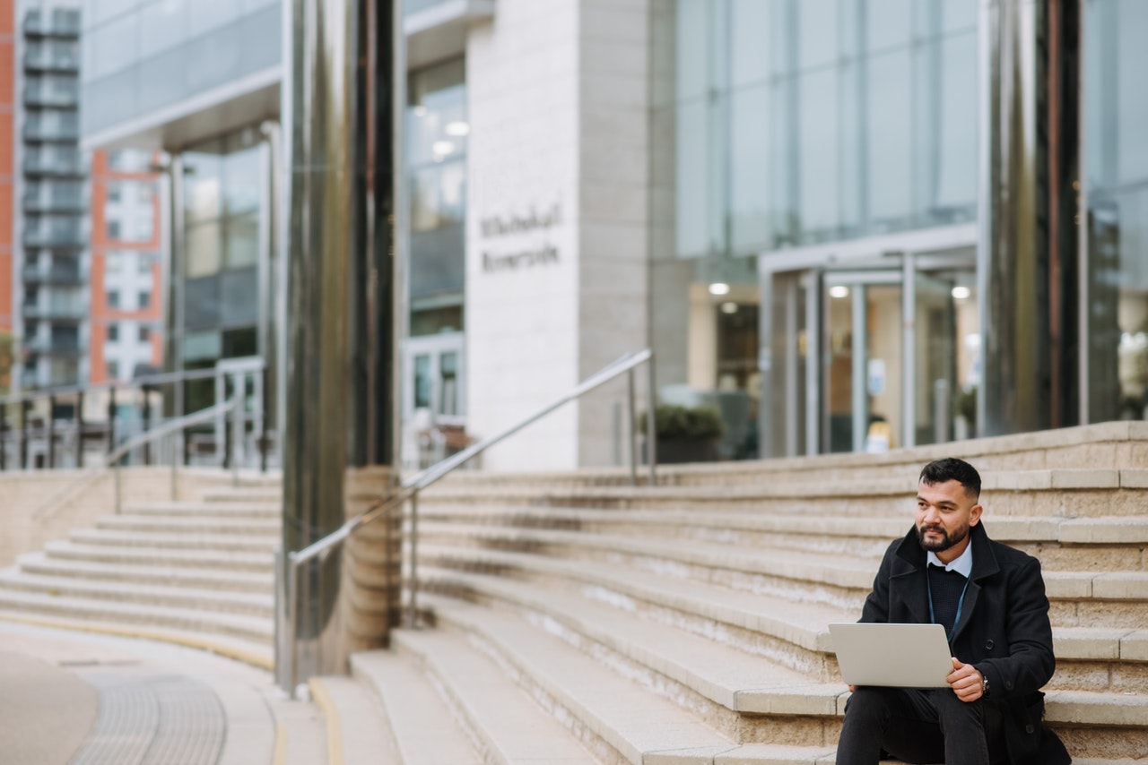 man using his laptop outside a building