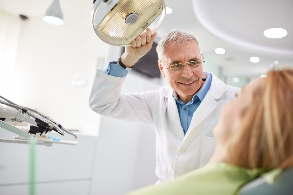 dentist holding the lights in his dental chair to direct on his patient's mouth