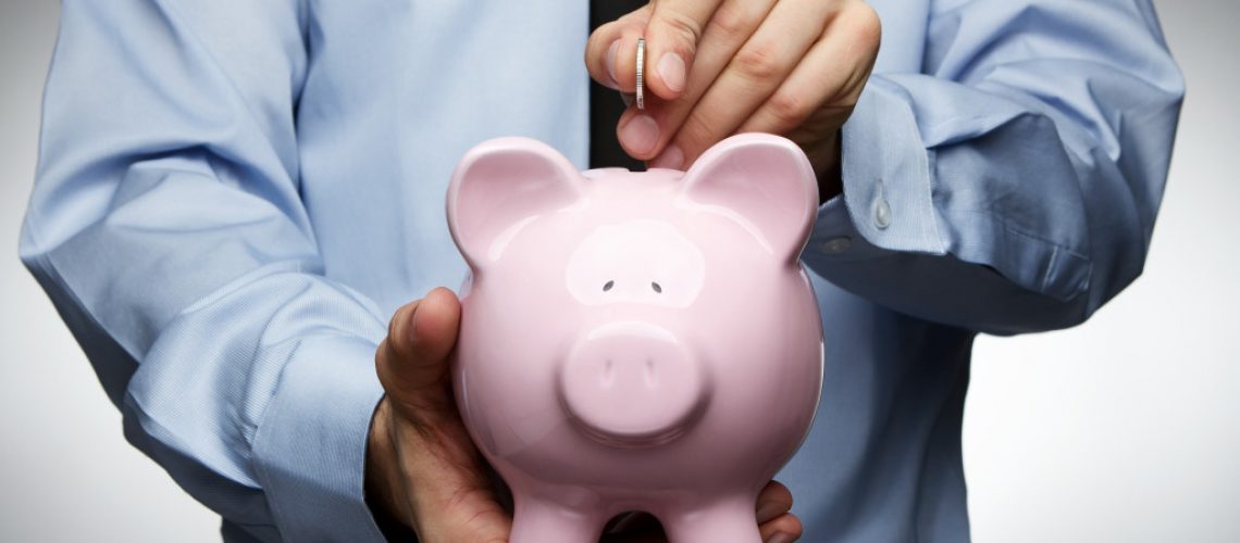A businessman putting a coin in a piggy bank