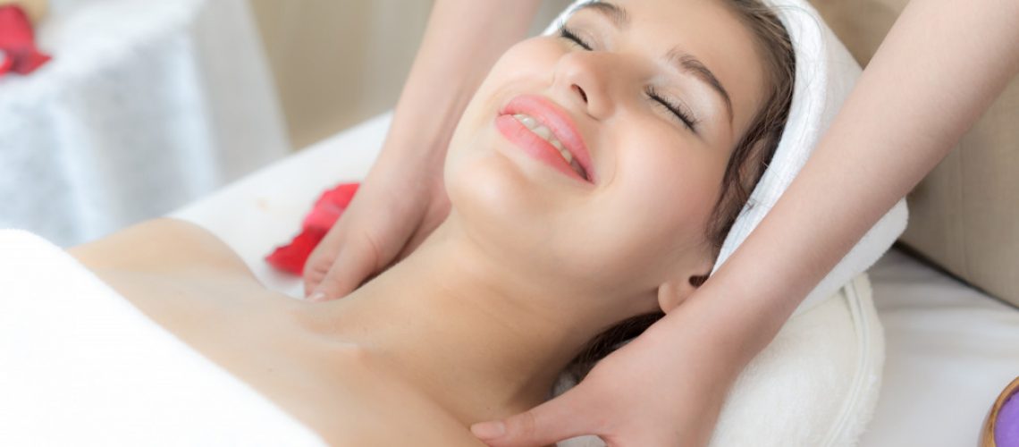 woman smiling while having her collarbone massaged